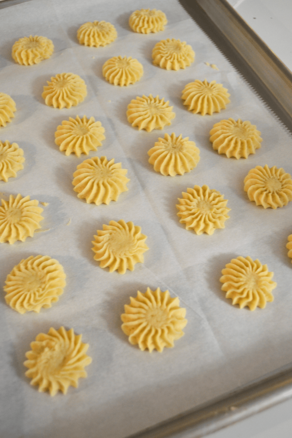 Would you like a refreshing Lemon flavored cookie? This recipe makes 21 -1" lemon buttercream filled sandwiched cookies, featuring a piped swirl using piping tip # 8 B. Made with fresh squeezed lemon juice, butter, cream cheese, egg yolk, sugar, and flour for prefect piping cookie dough. Easy recipe and so delicious to eat. Get the recipe at lizbushong.com. Lemon you are the Zest! Serve these cookies on any occasion for a refreshing two bite treat. #lemon #cookies #dessert #mini #recipe